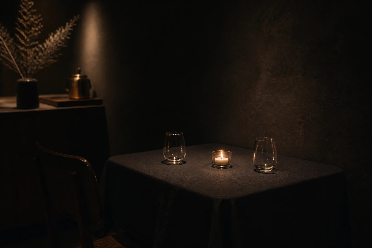 Kleiner Tisch für zwei mit Kerze und Gläsern im warmen Licht
